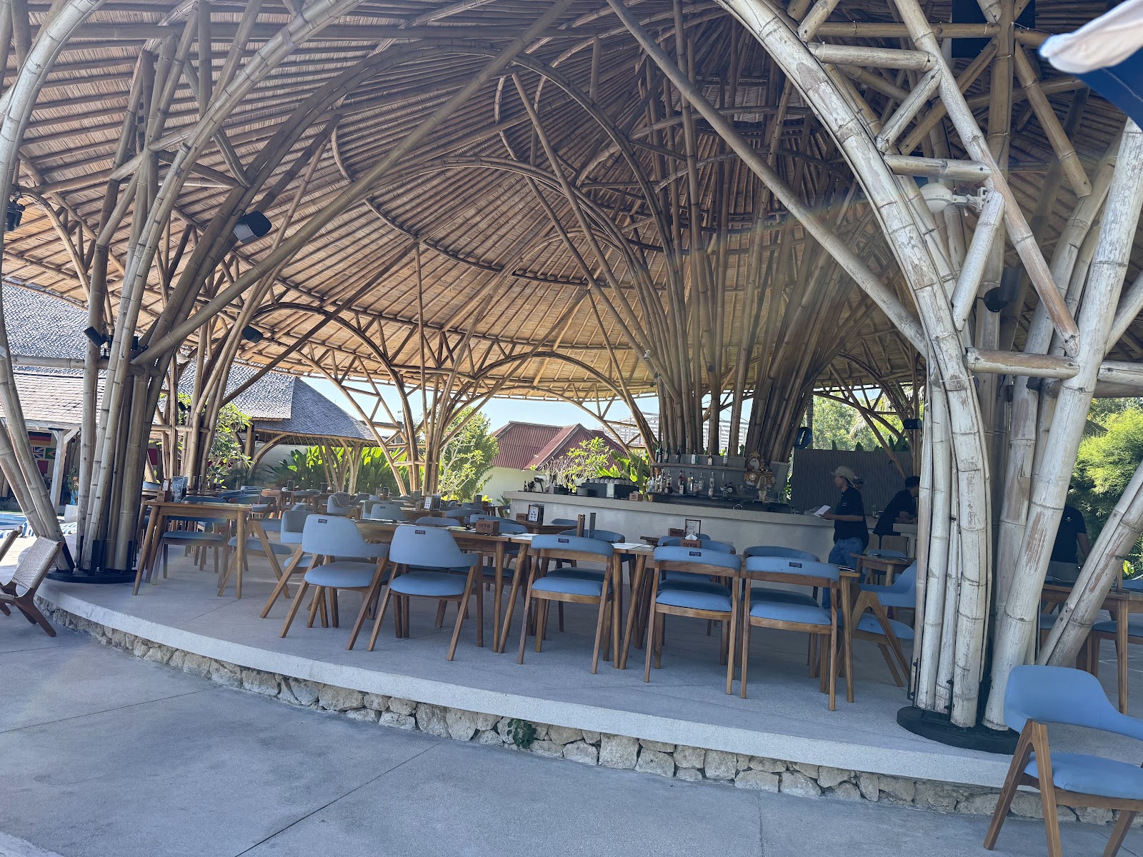 Restaurant tables under the bamboo roof at Orca Beach Club