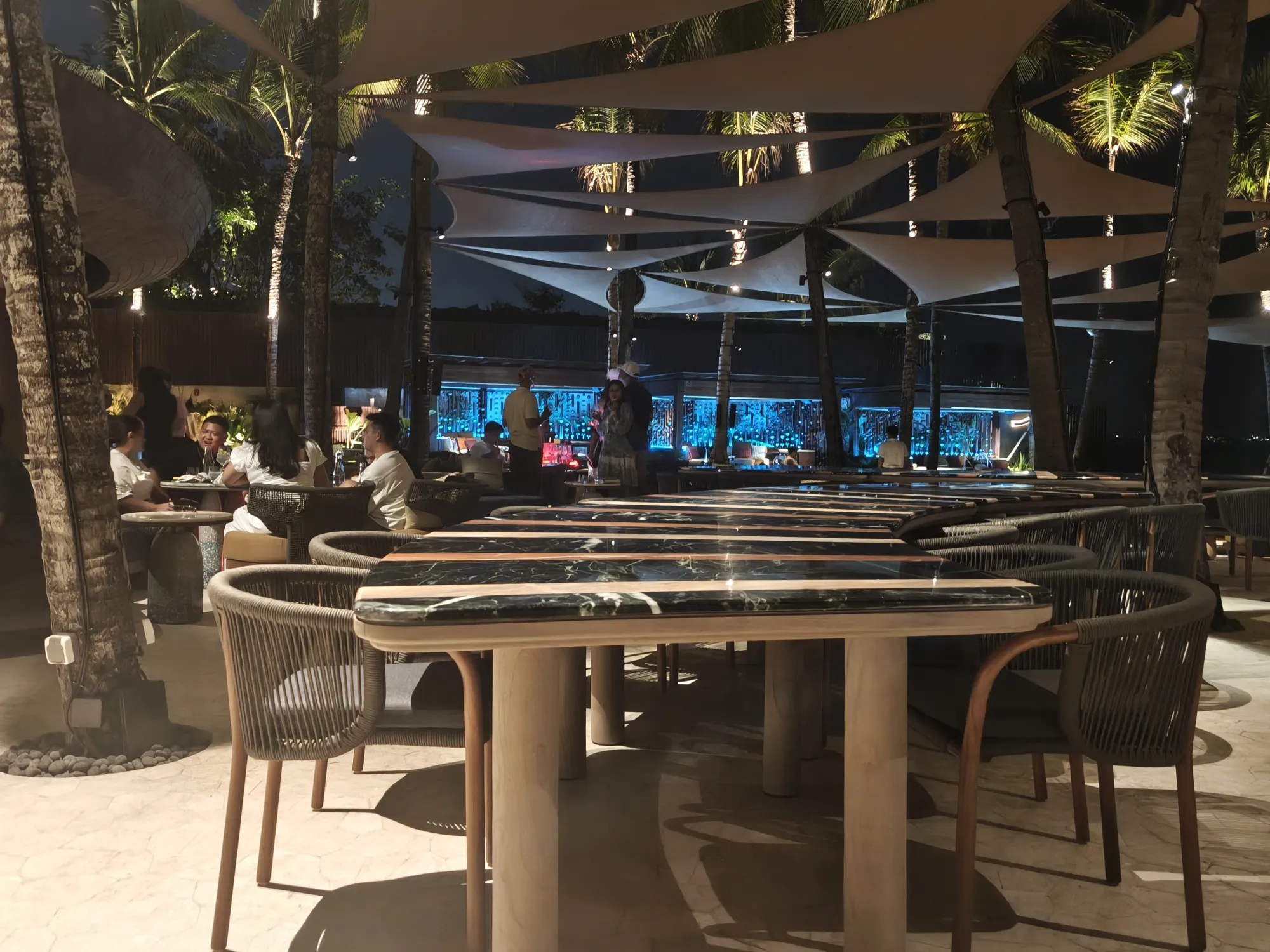 Dining tables and chairs under shade sails at Alune Beach Club