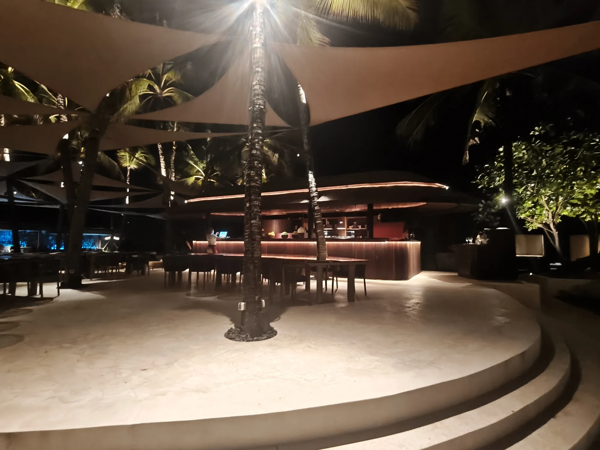 Open-air lounge and bar area inside the beach club at night