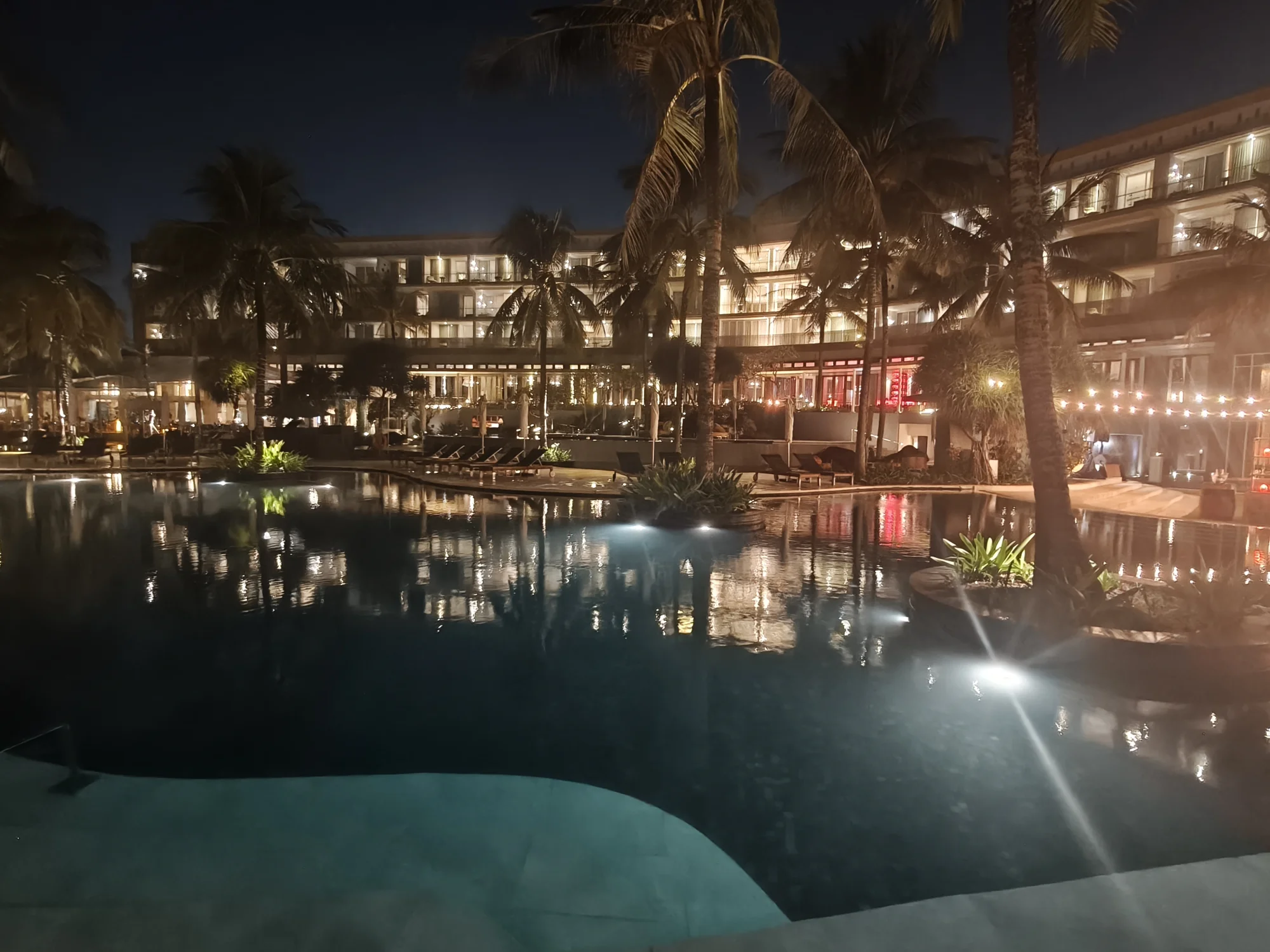 Resort pool reflecting the lights of W Bali Seminyak at night