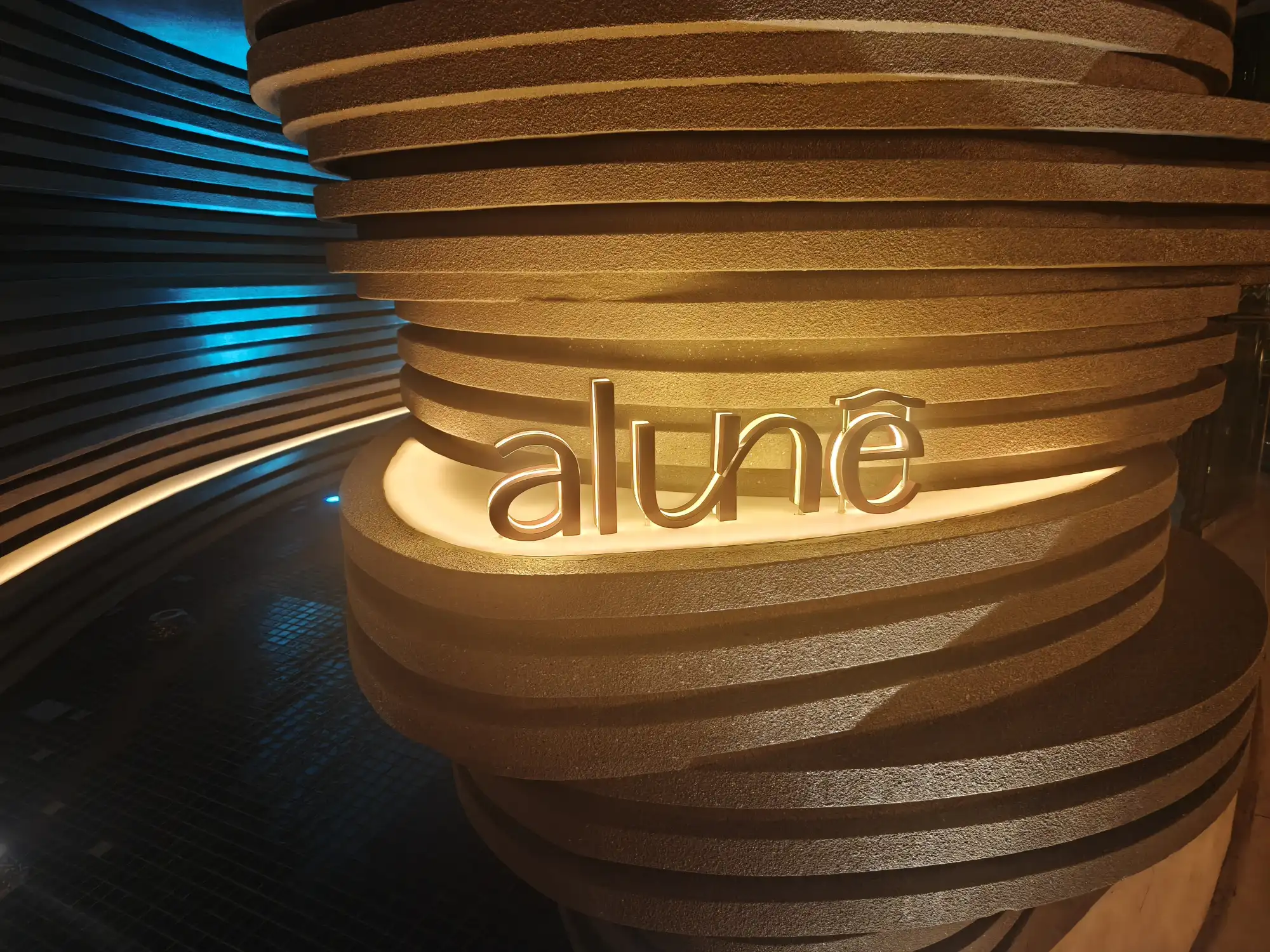 Illuminated Alune sign at the entrance of Alune Beach Club