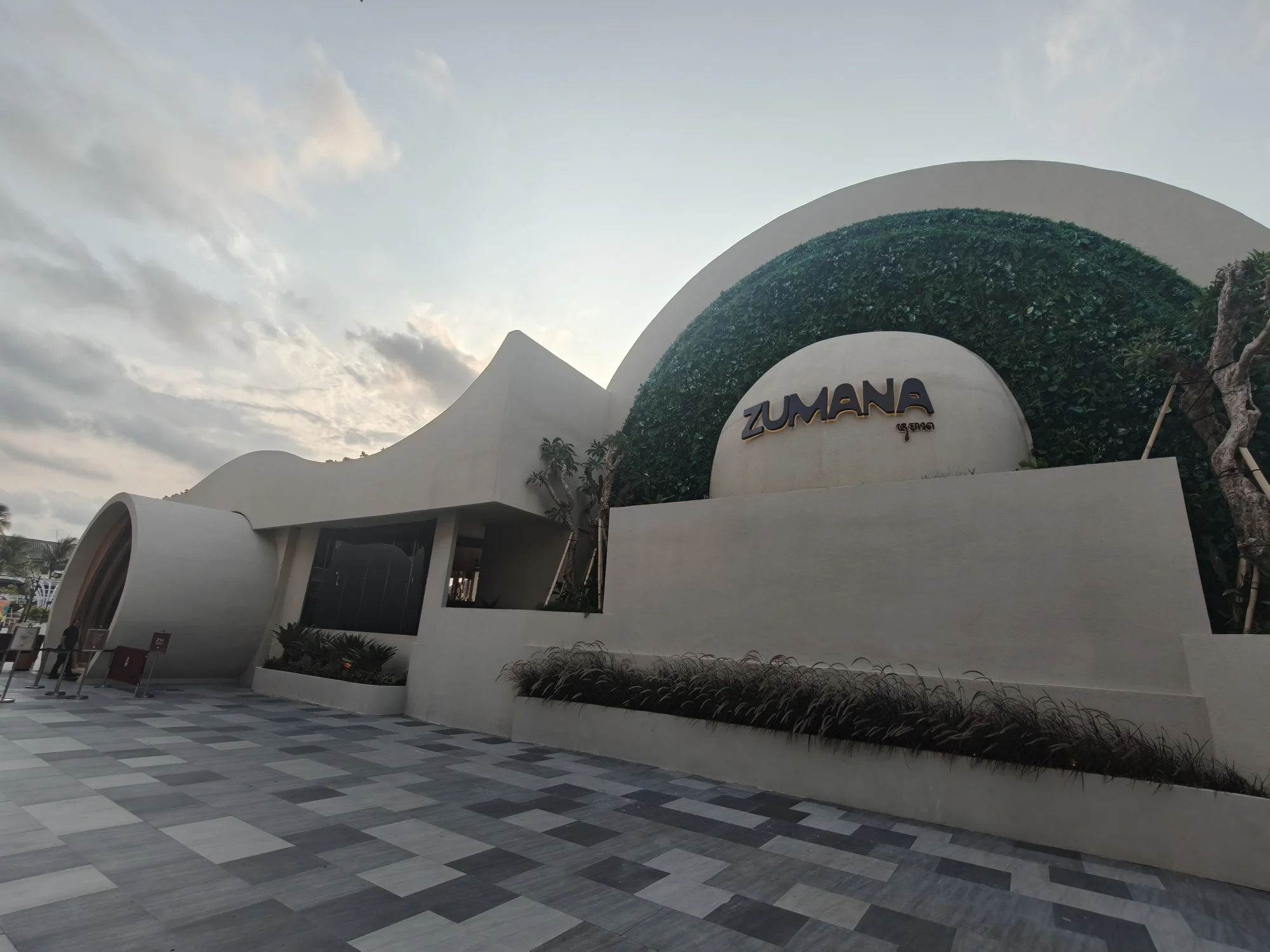 Zumana Beach Club entrance with its curved white facade in Kuta