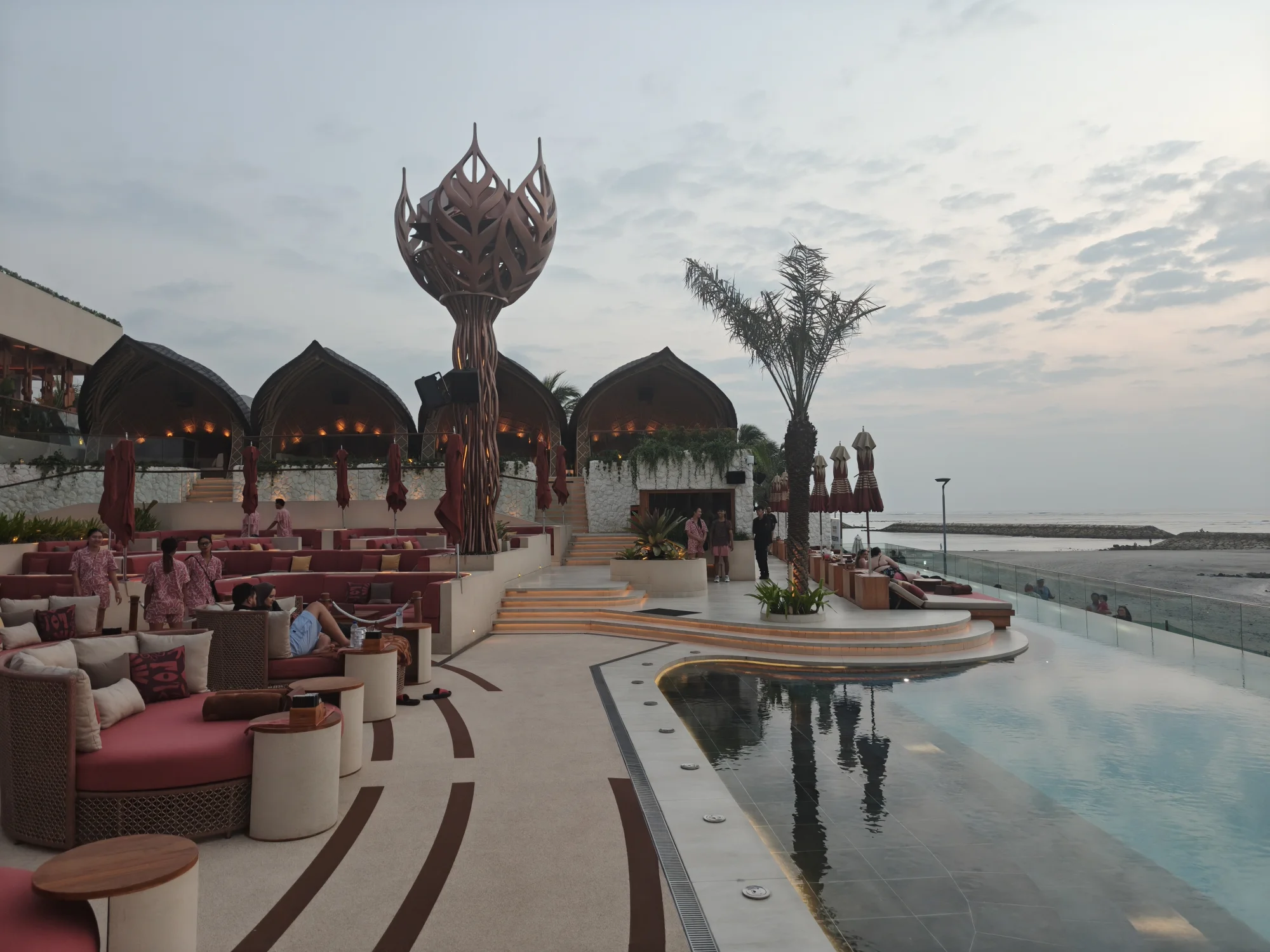Thatched daybeds lined along the infinity pool at Zumana Bali